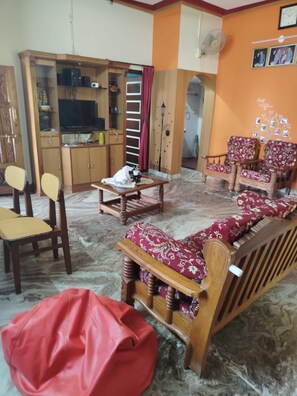 A living room with a sofa, chairs, a coffee table, and a television.