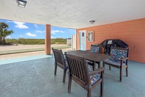 An outdoor patio with a table and chairs, a grill, and a view of the beach. - Ground Floor Beachfront Condo. Heated Pool. Shuffleboard. Perfect Location. No Car Necessary! (Treasure Island)