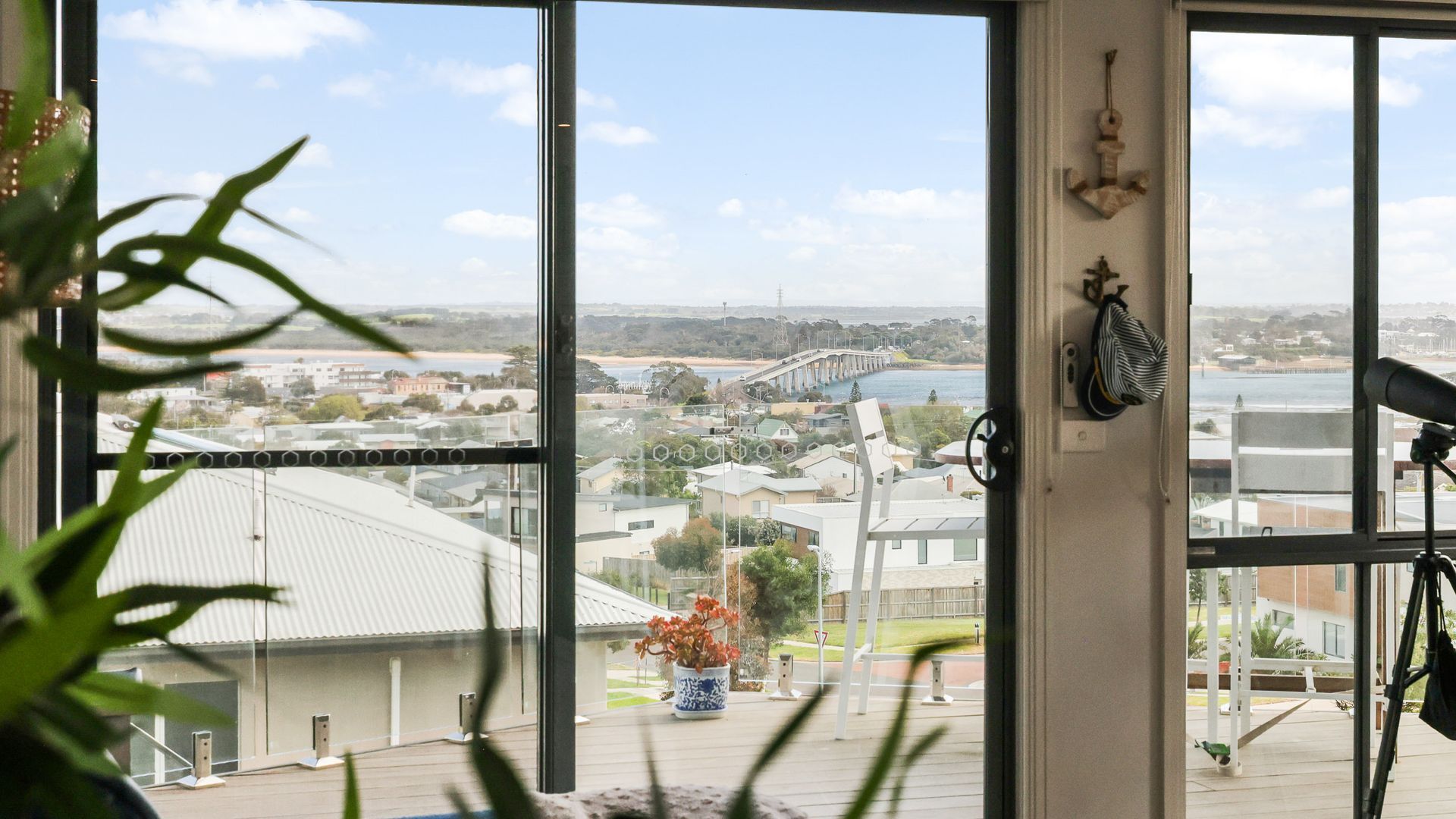Ein Zimmer mit großem Fenster und Blick auf eine Brücke und einen Strand.