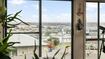 Ein Zimmer mit großem Fenster und Blick auf eine Brücke und einen Strand.