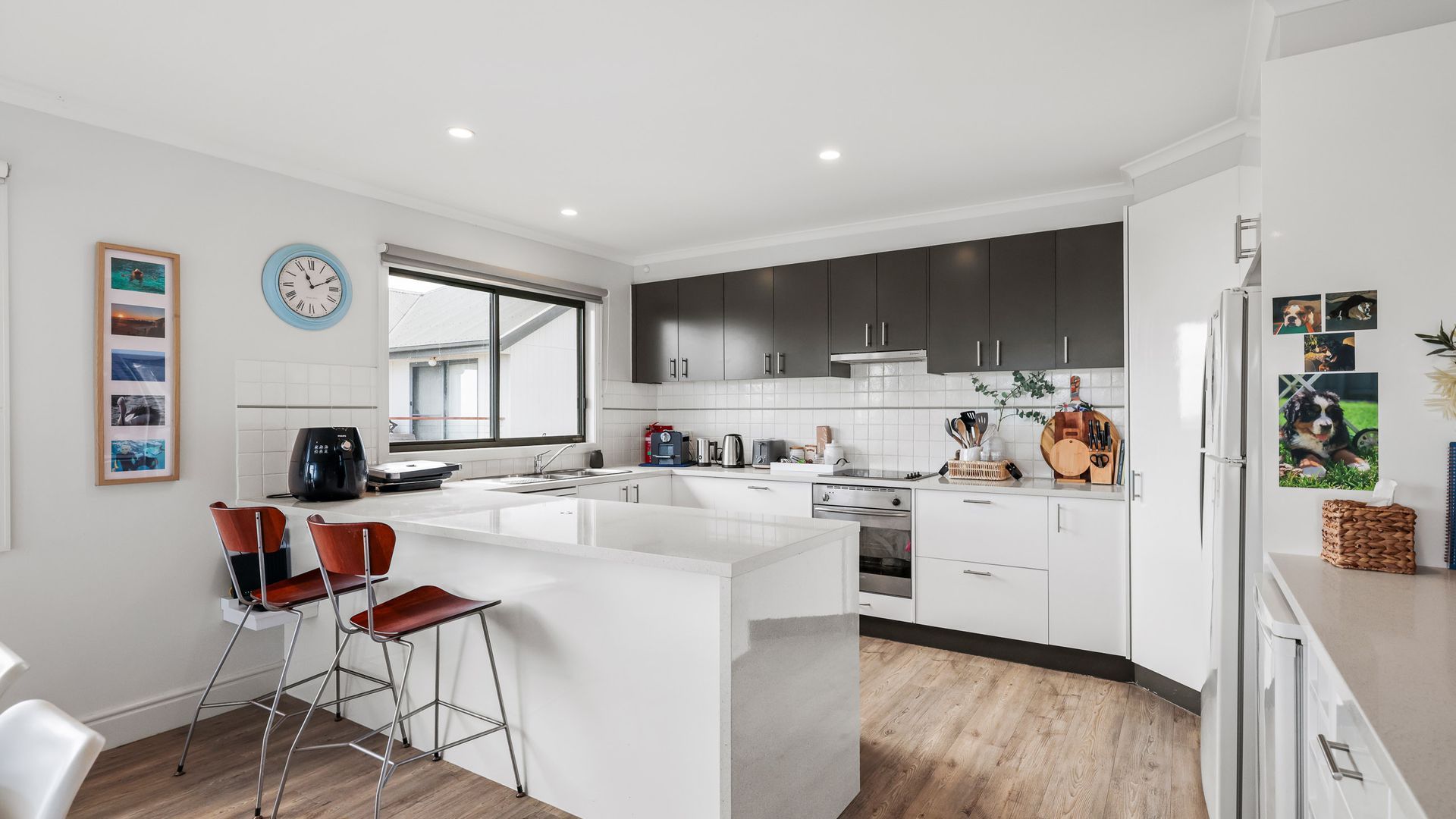 Cocina moderna con armarios blancos, una isla grande y un ventanal que aporta luz natural.