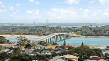 A coastal bridge with a clear view of the surrounding landscape, including residential buildings and a beach.