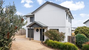 A two-story residential building with a driveway, a front door, and a small porch. - Panorama Bay Escape San Remo (San Remo)