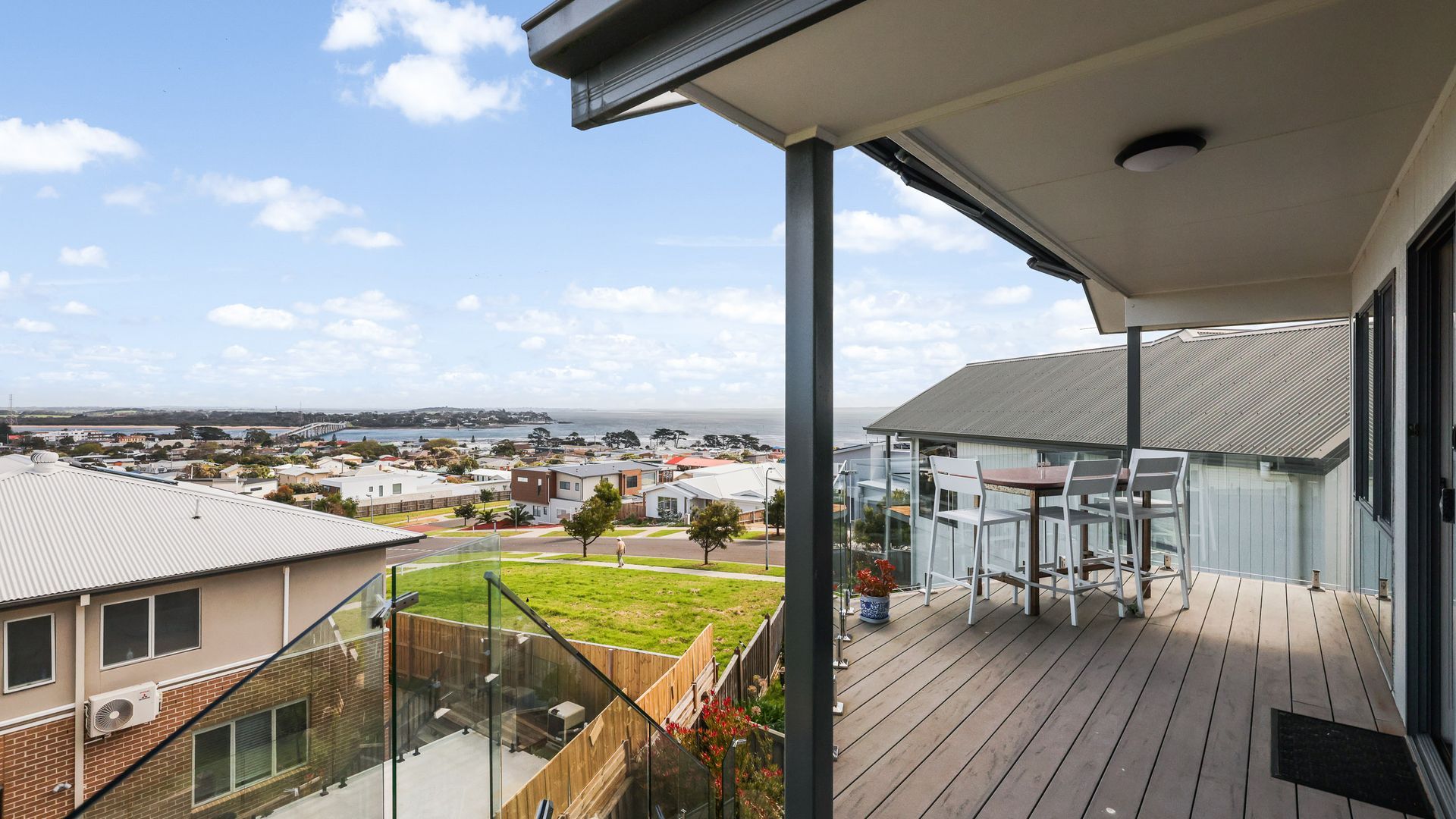 A balcony with a view of a residential area and the sea.