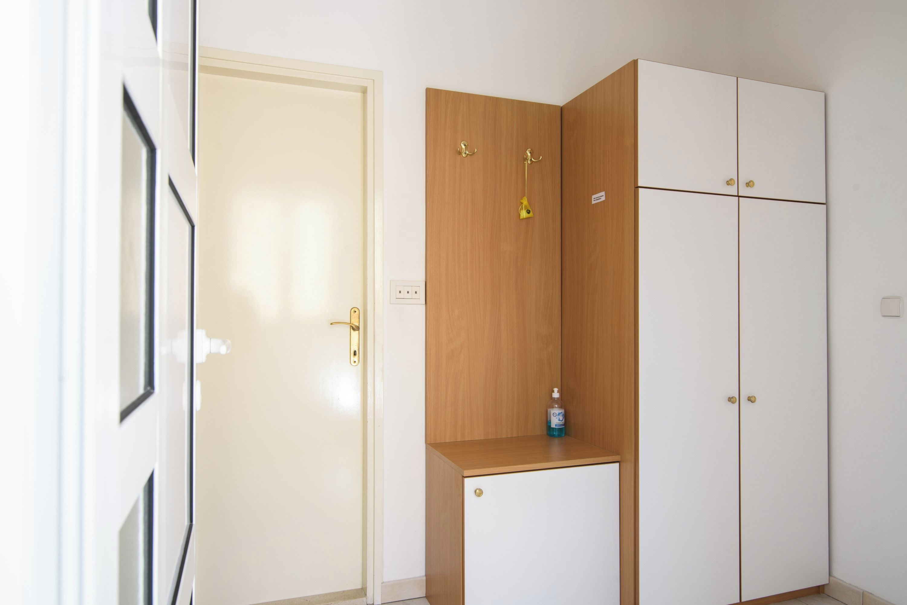 Une pièce avec une porte blanche, un meuble en bois et une armoire blanche.