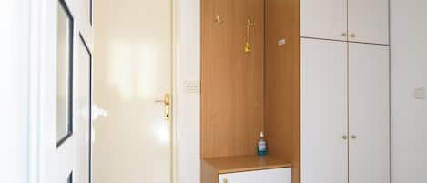 A room with a white door, a wooden cabinet, and a white wardrobe.