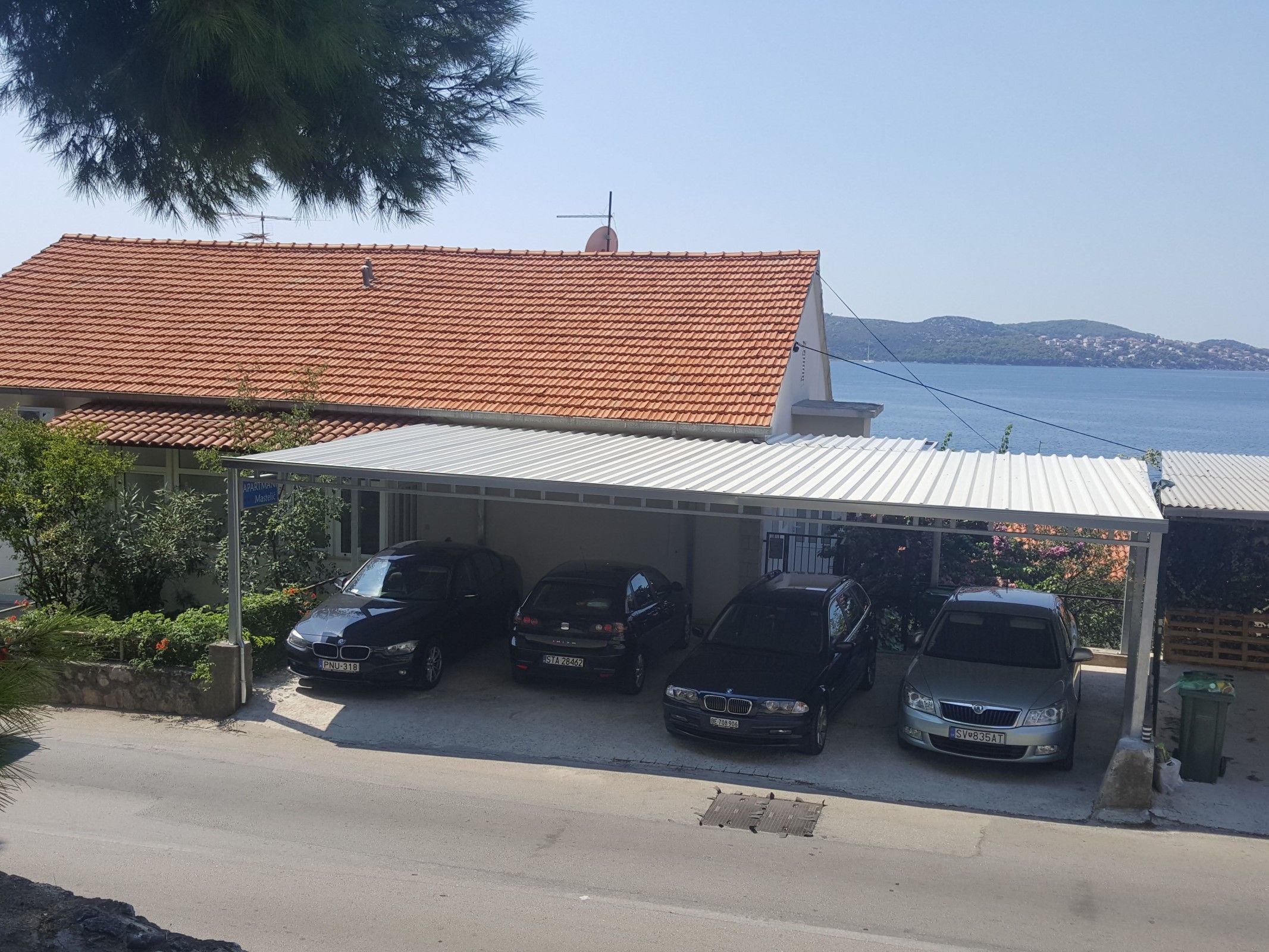 En byggnad med ett rött tegeltak och ett överbyggt parkeringsområde med plats för fyra bilar.