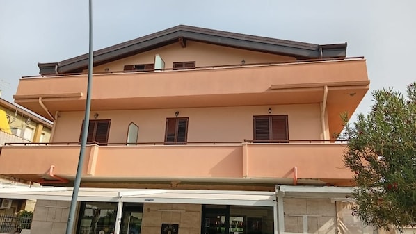 Un immeuble de deux étages, doté d’un toit plat et d’un balcon à l’étage supérieur.