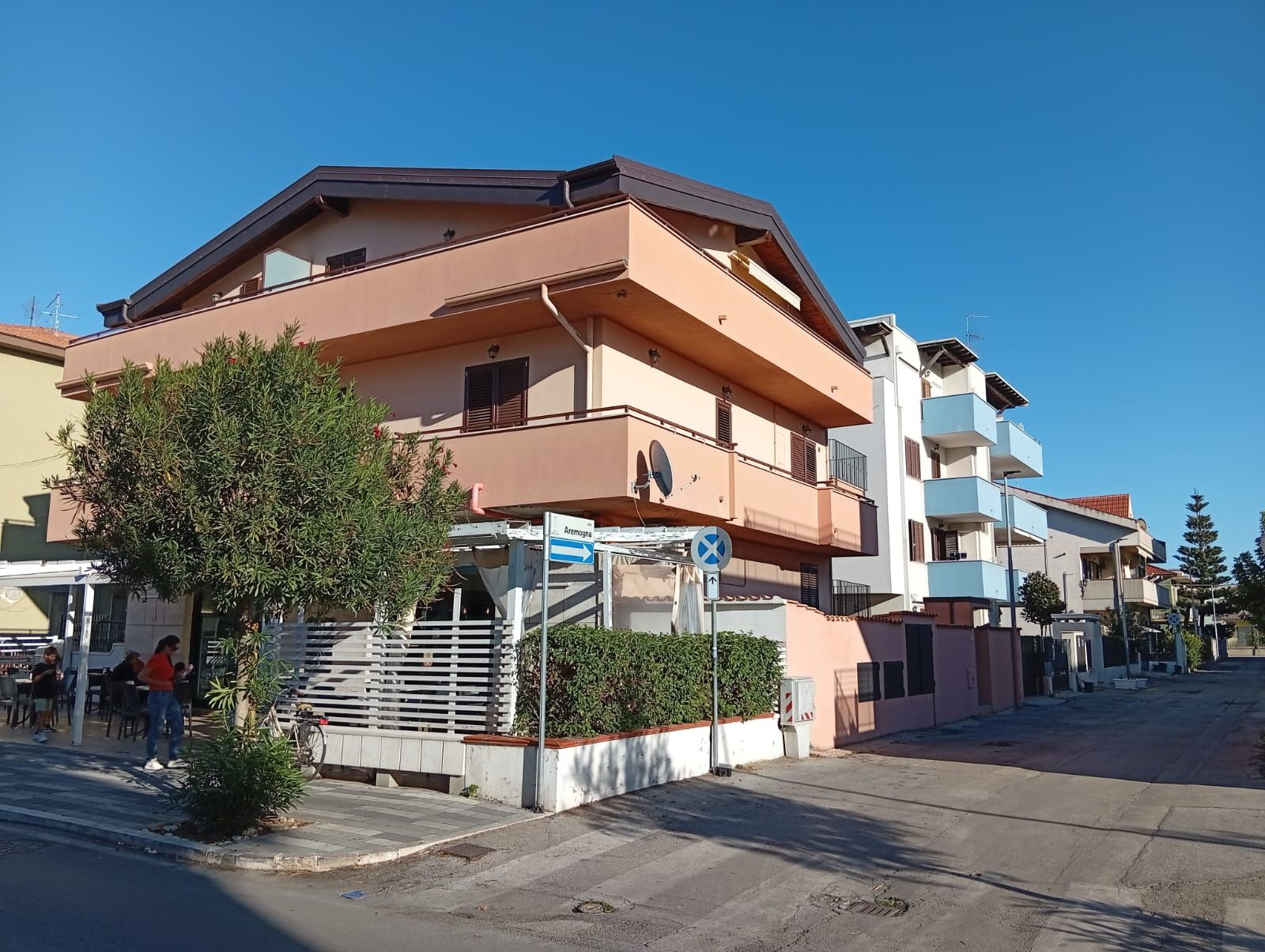 Un edificio residencial de varios pisos con balcones, un acceso con portón y cielo despejado.
