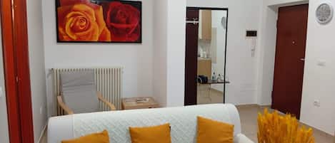 A modern bedroom with a bed, a chair, a painting, and a vase of flowers.