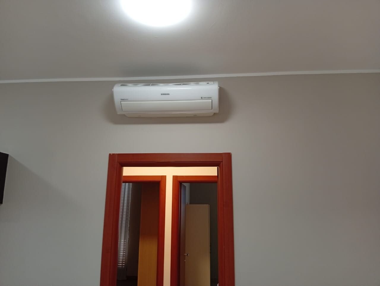 Een kamer met een witte airconditioning die aan de muur boven een rode deur is bevestigd.