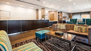 Un lobby moderno con una recepción, zona de estar y un área de comedor.