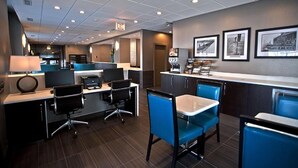 A hotel lobby with a reception desk, seating area, and framed pictures on the wall.