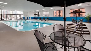 A swimming pool with lounge chairs and tables, large windows, and a view of buildings outside. - 3 Standard Double Rooms | Pool | River North Chicago (Chicago)