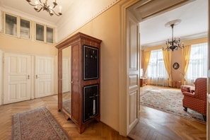 Ein geräumiges Zimmer mit einem großen Holfachschrank, einem roten Sessel und einem gemusterten Teppich.