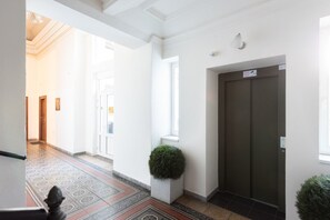 En hall med ett mönstrat golv, en dörr och en väggmonterad lampa.