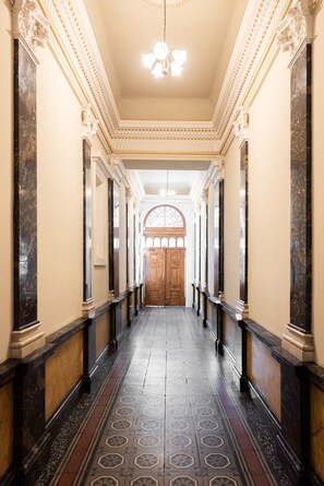 A hallway with a marble floor, columns, and a wooden door at the end. - Charming 2BR Apt. near the National Museum by EasyBNB Premium (Prague)