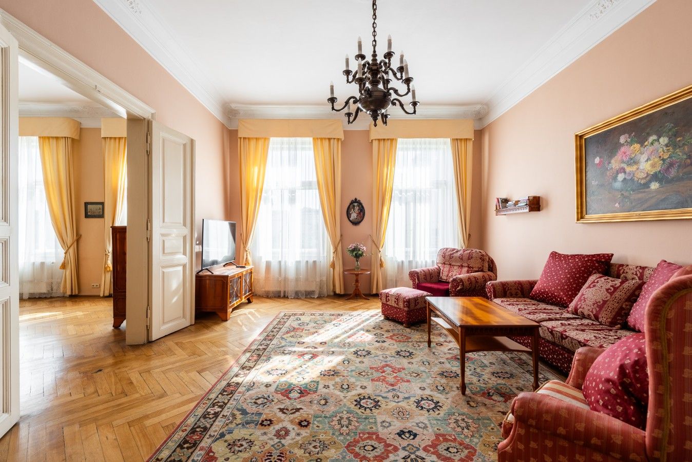 A living room with a sofa set, a coffee table, a TV, and a patterned rug.
