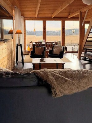 Ein gemütliches Zimmer mit einer Couch, einem Tisch und Blick ins Freie.
