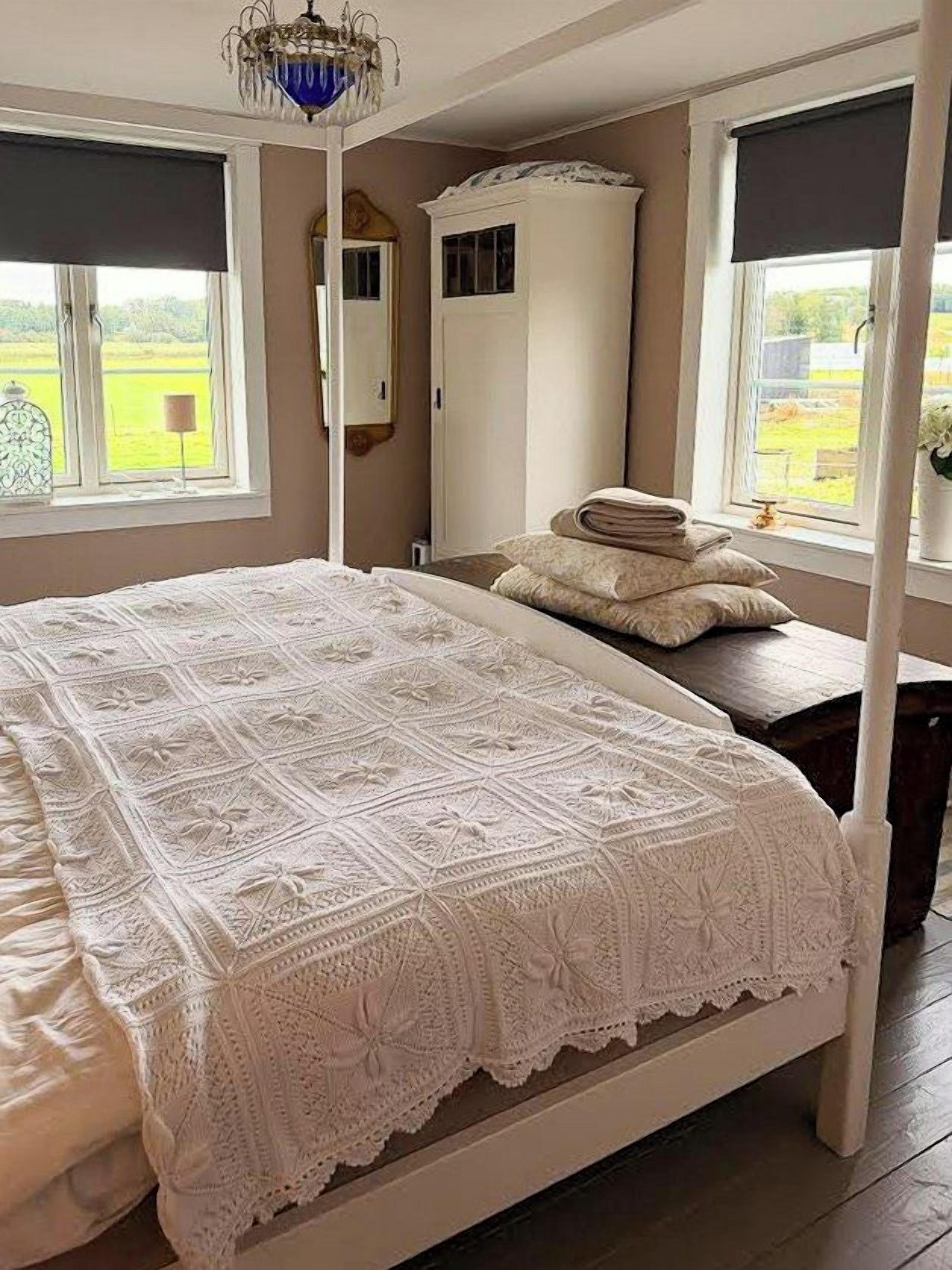 Une chambre avec un grand lit, une armoire et une fenêtre donnant sur un beau paysage.