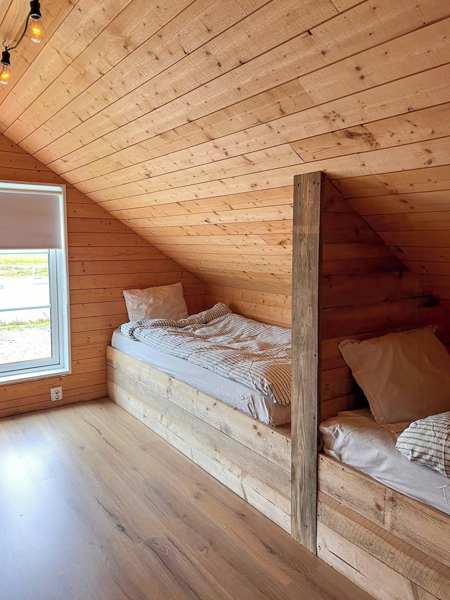 A small, cozy attic bedroom with a sloped ceiling, a single bed, and a window.