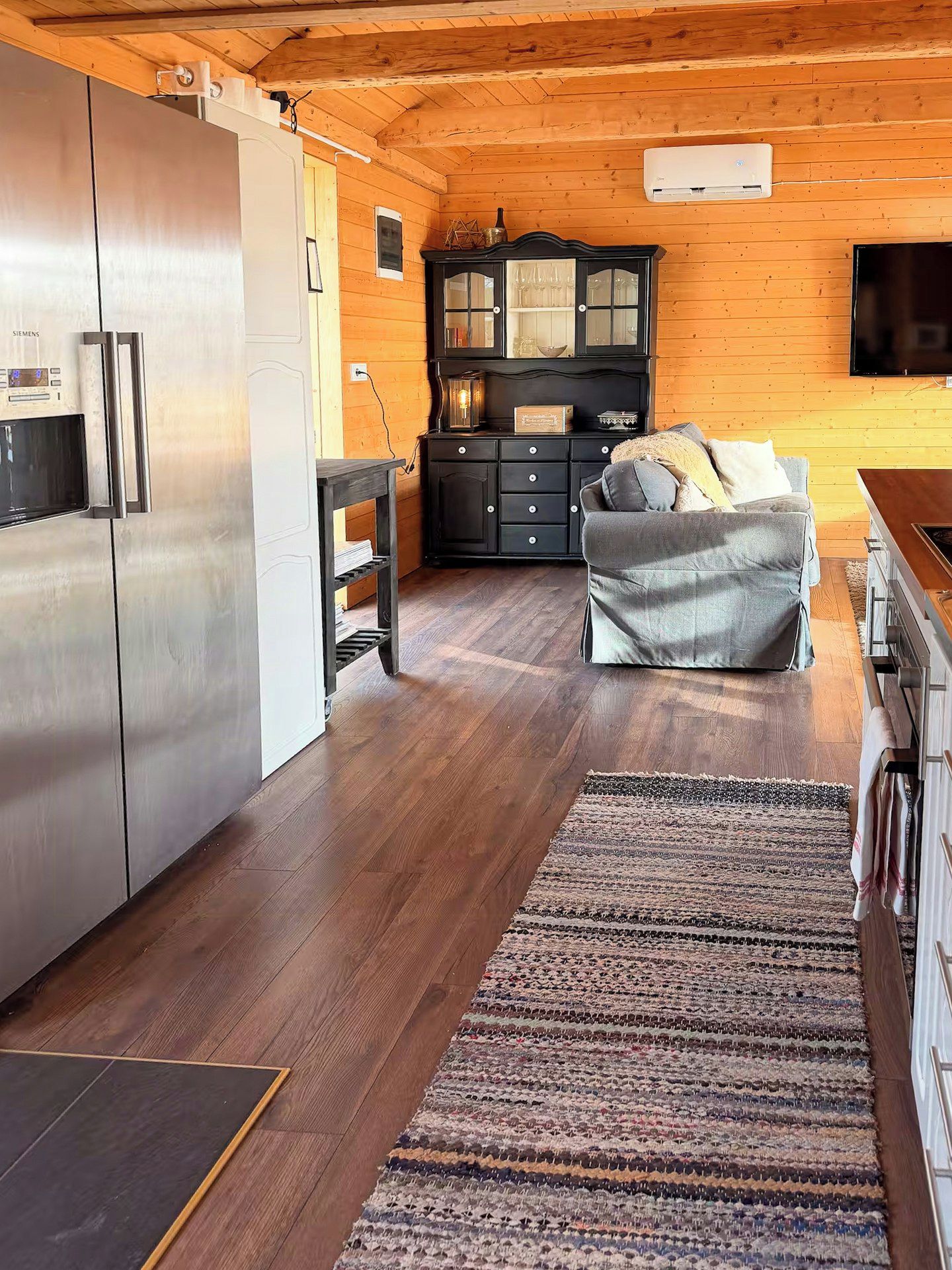 A modern kitchen with a stainless steel refrigerator, wooden cabinets, and a built-in oven.