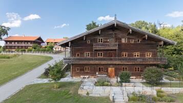 A large wooden building with multiple balconies, a paved driveway, and a well-maintained lawn.