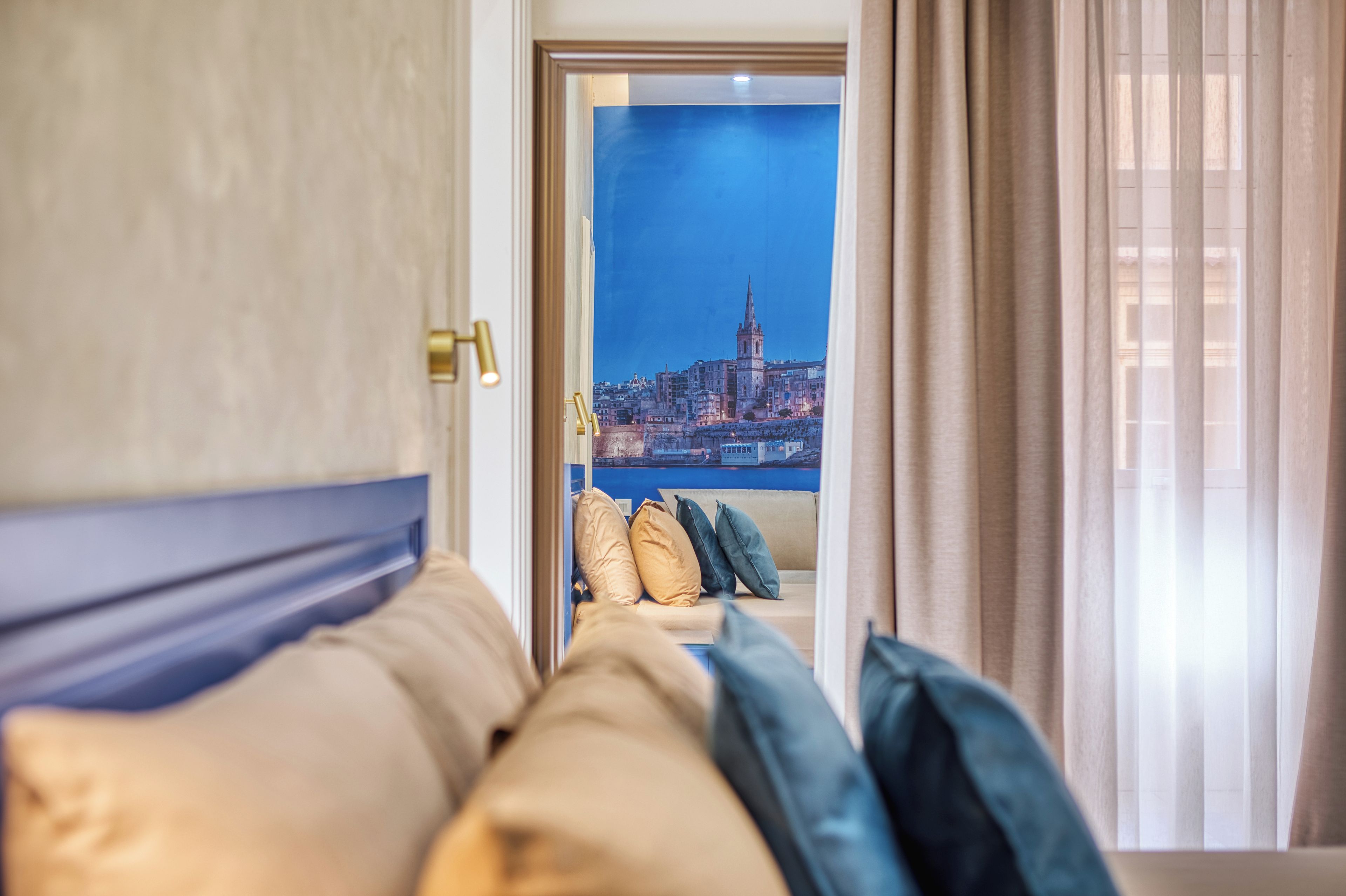 A hotel room with a bed, a view of a cityscape, and a window with curtains.