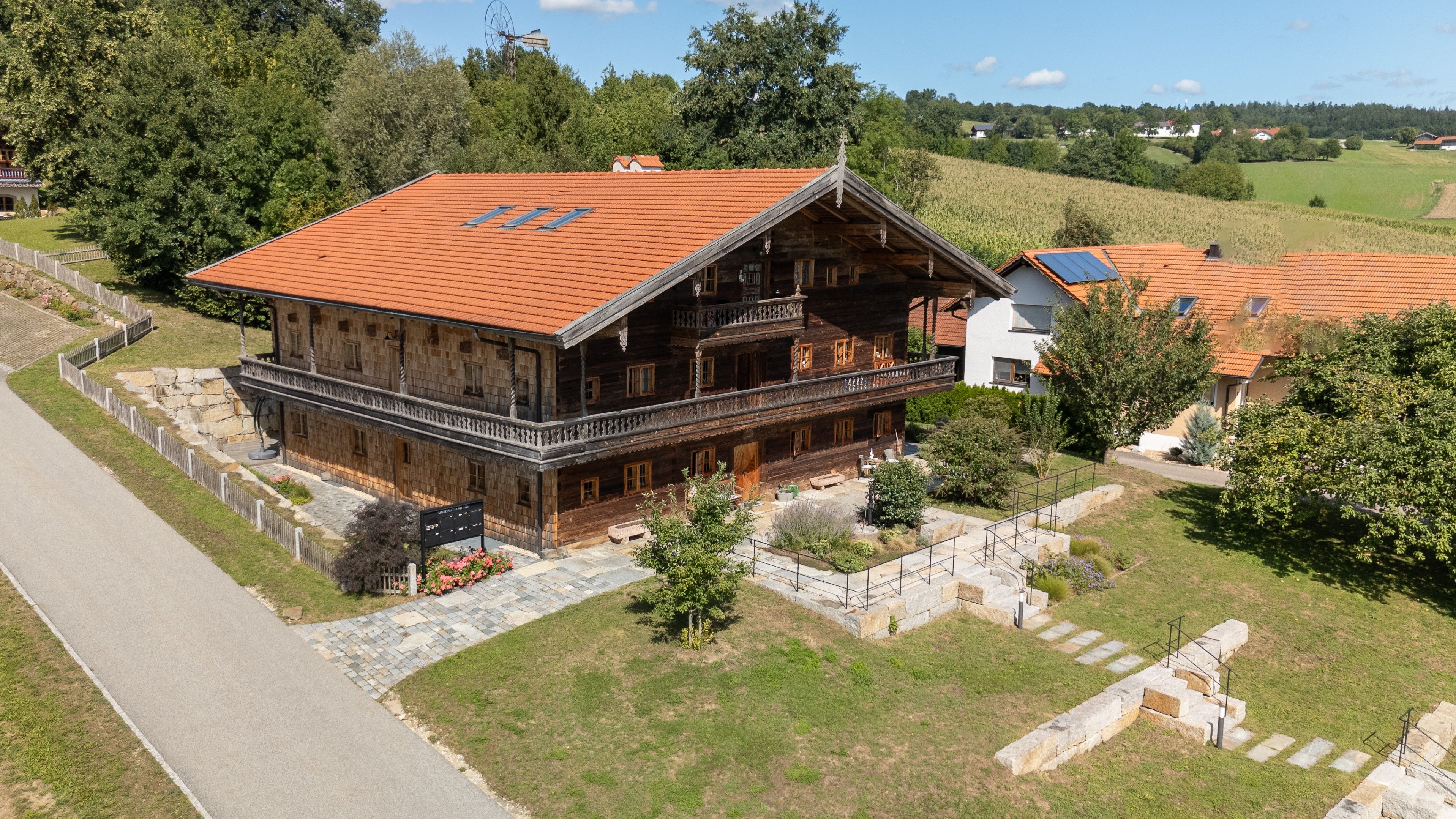 A traditional wooden house with a sloped roof, a balcony, and a stone pathway leading to the entrance.