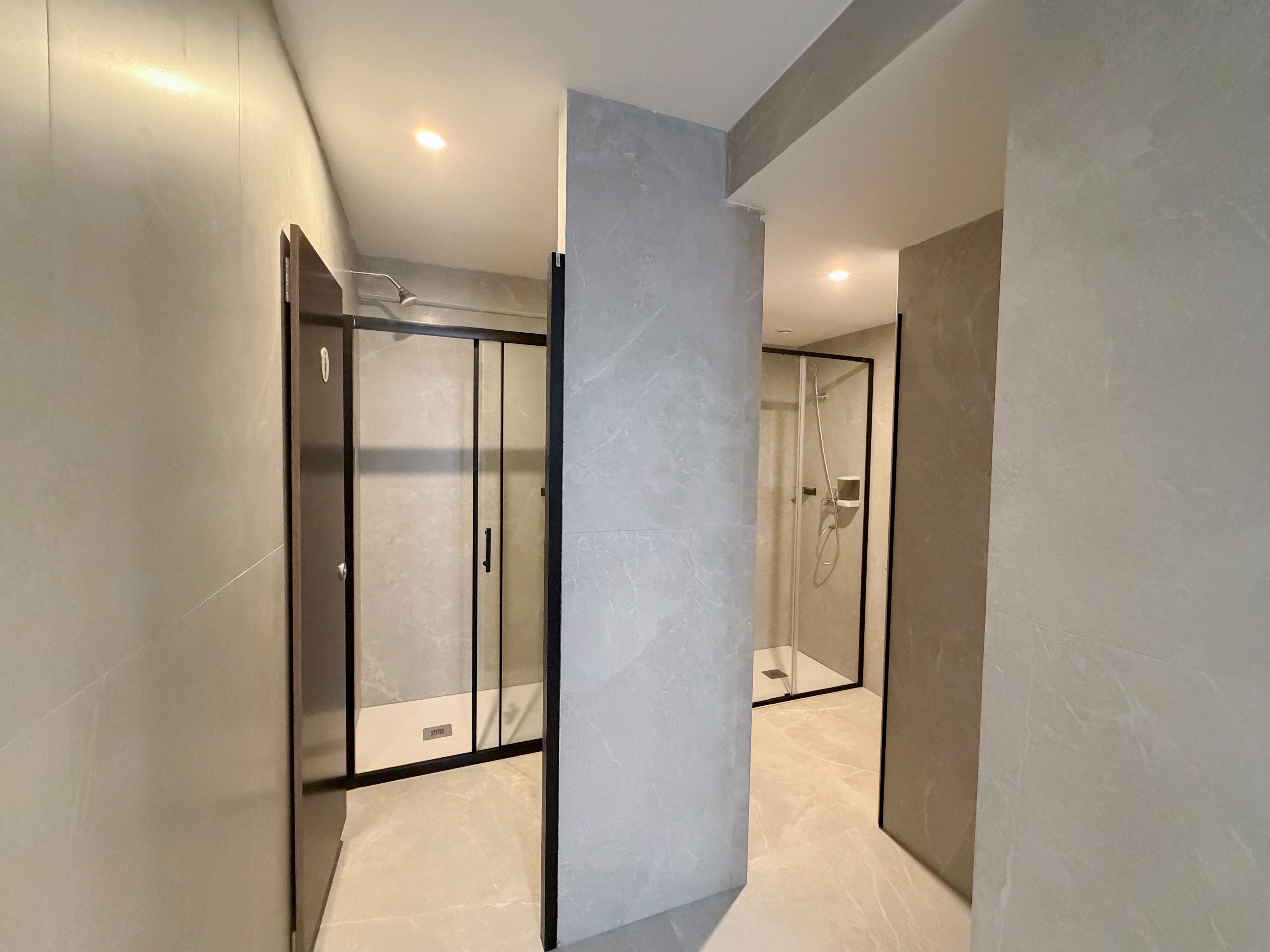 Une salle de bain moderne avec une douche à parois de verre, un sol en marbre et un éclairage encastré au plafond.