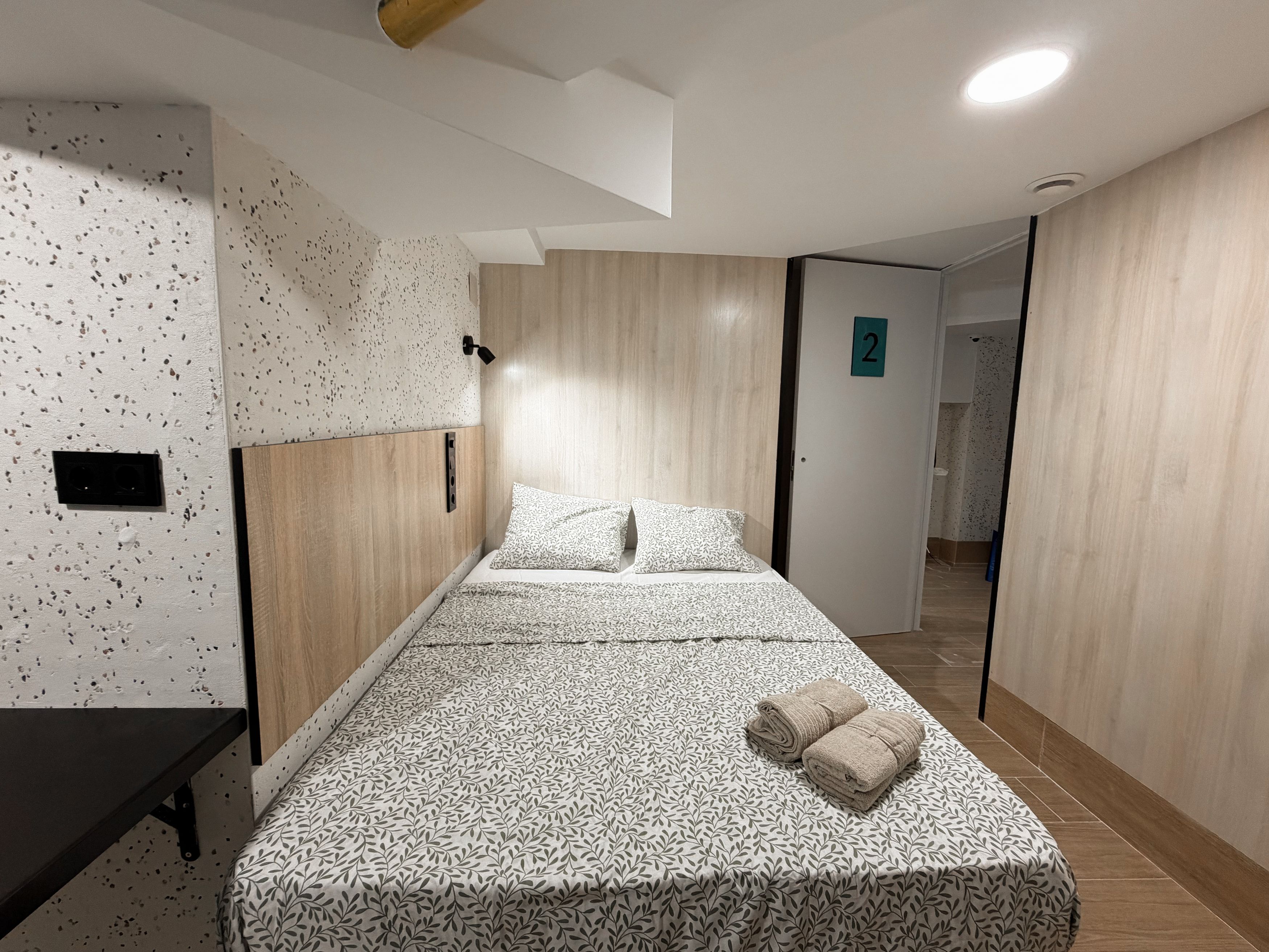 A modern hotel room with a bed, a desk, and a wardrobe.