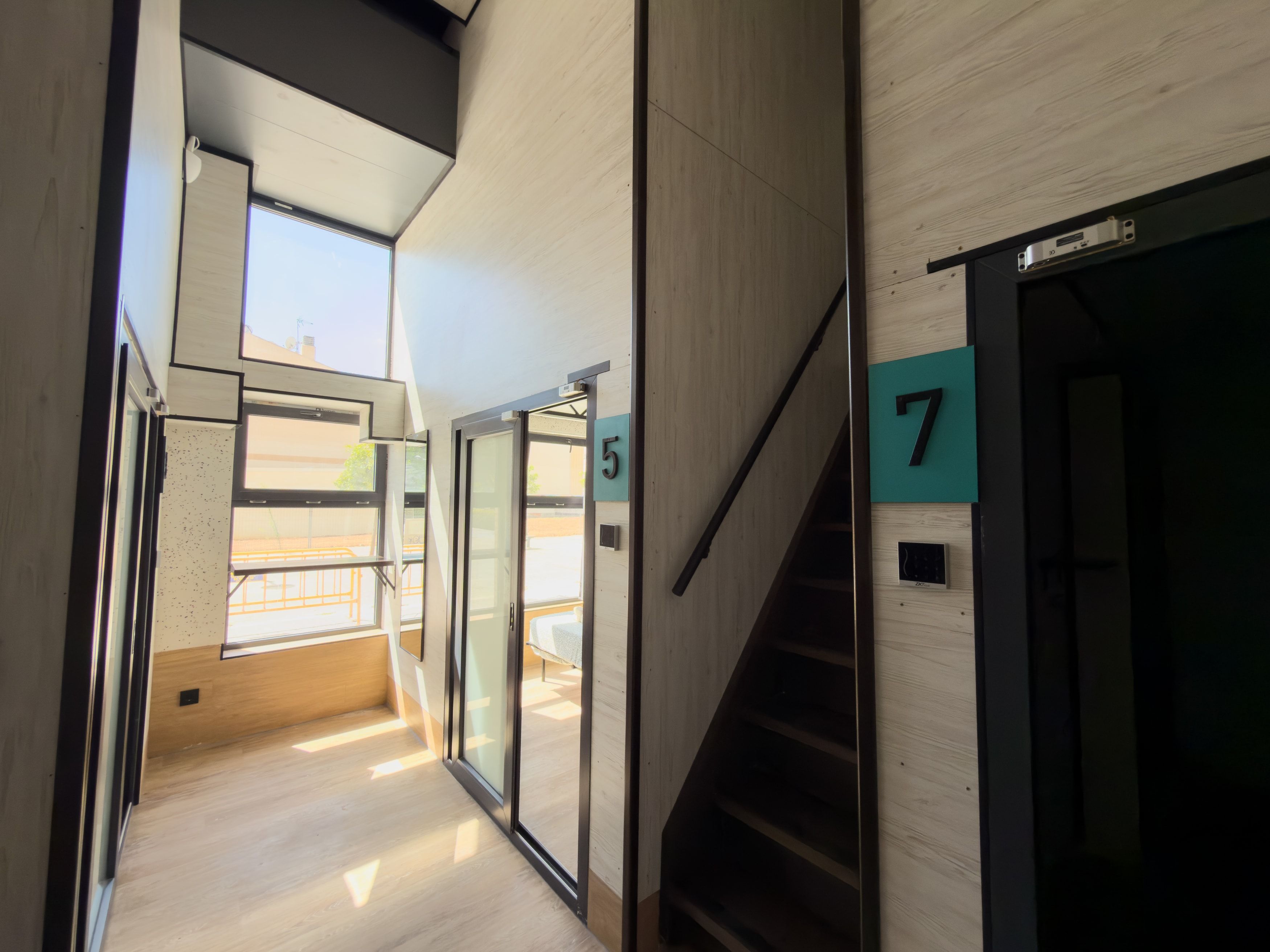 A modern interior with a staircase, glass doors, and wooden flooring.