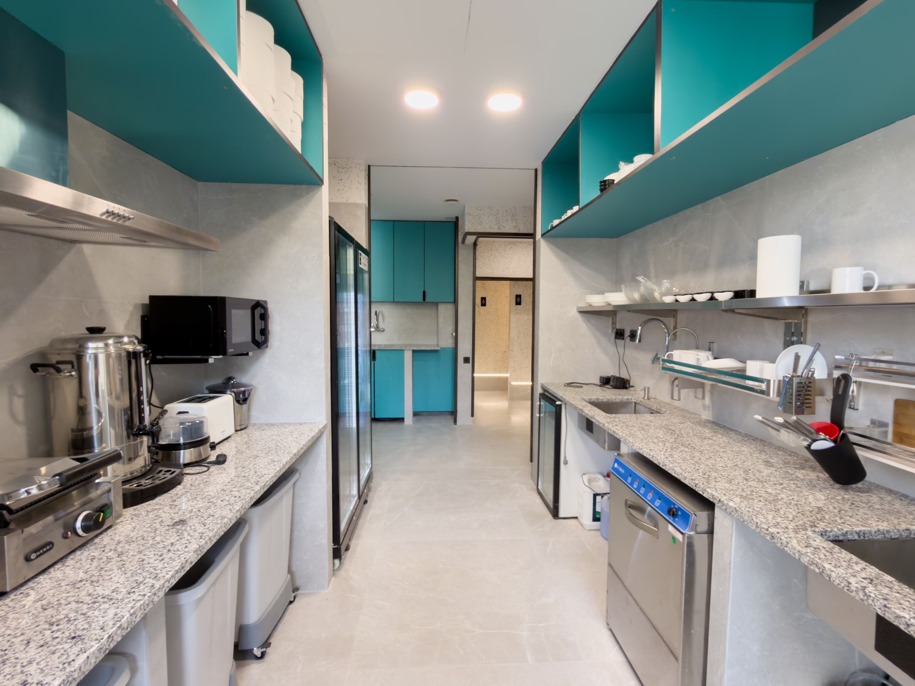 Une cuisine moderne dotée d’appareils électroménagers en acier inoxydable, de meubles de couleur turquoise et d’un îlot central.