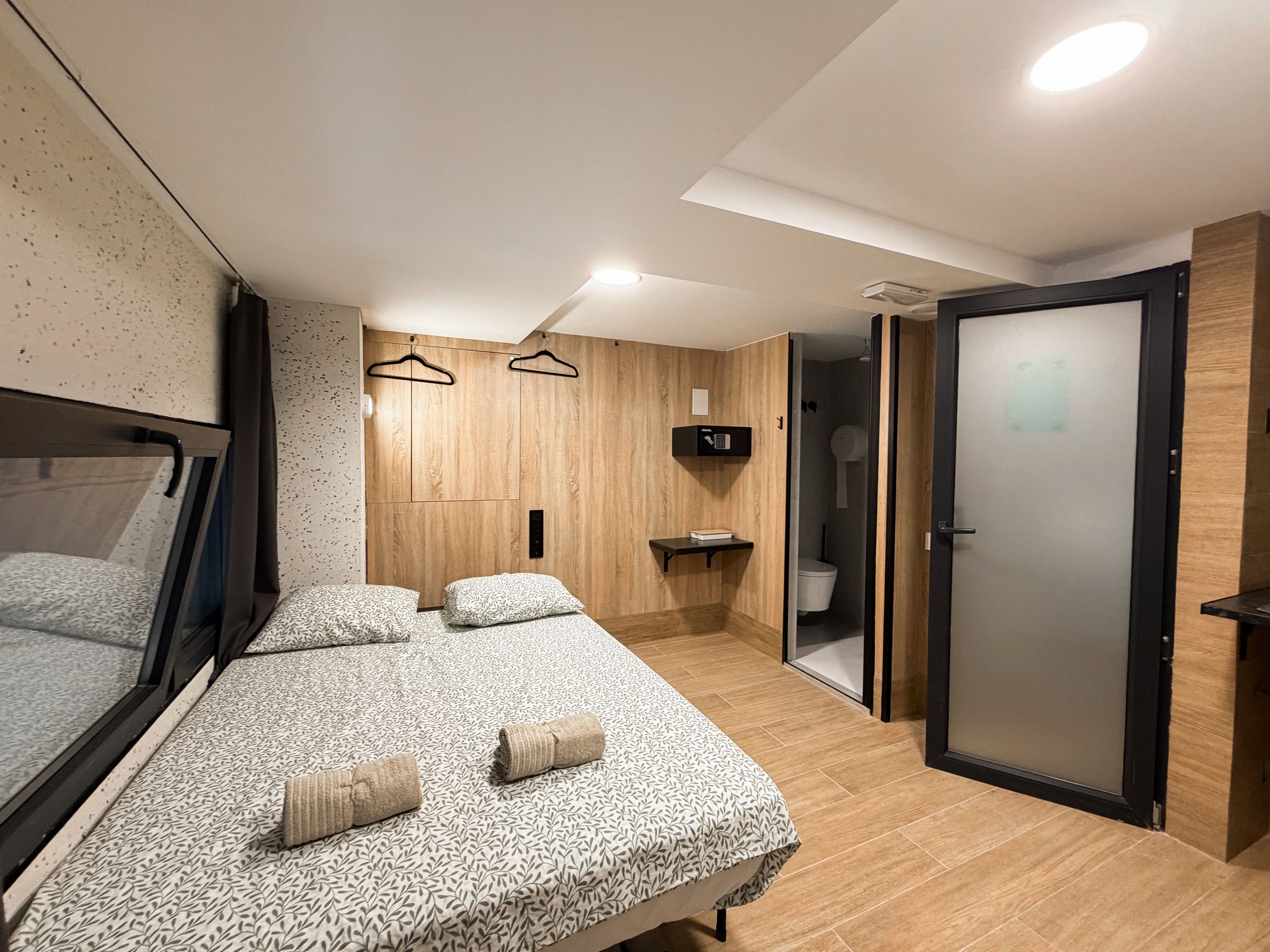 Un dormitorio moderno con una cama grande, mesitas de noche, un armario y un baño con inodoro y ducha.