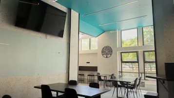A modern conference room with a large table, chairs, a flat-screen TV, and large windows.