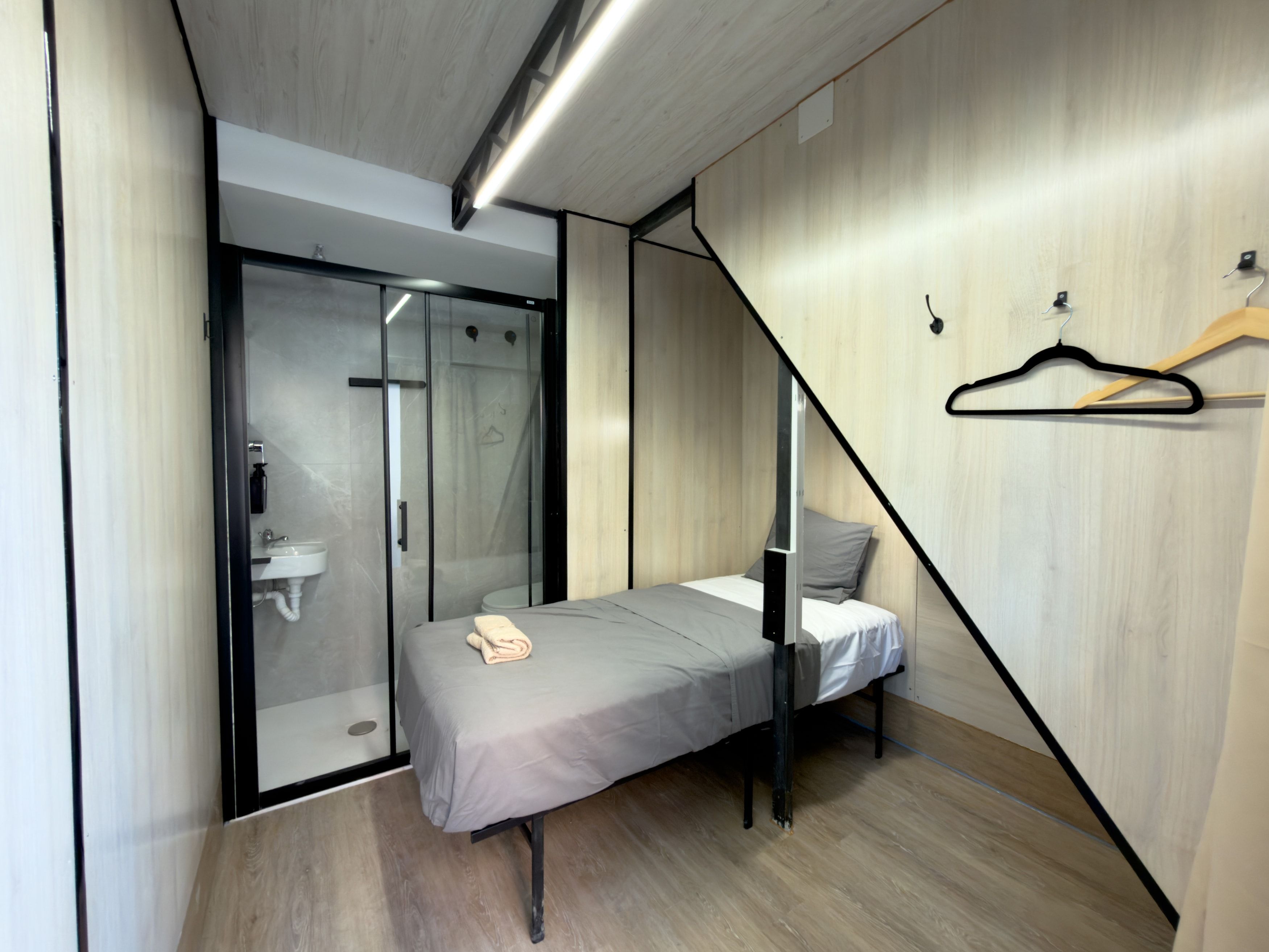 Un dormitorio pequeño con cama, ducha y pared de madera.