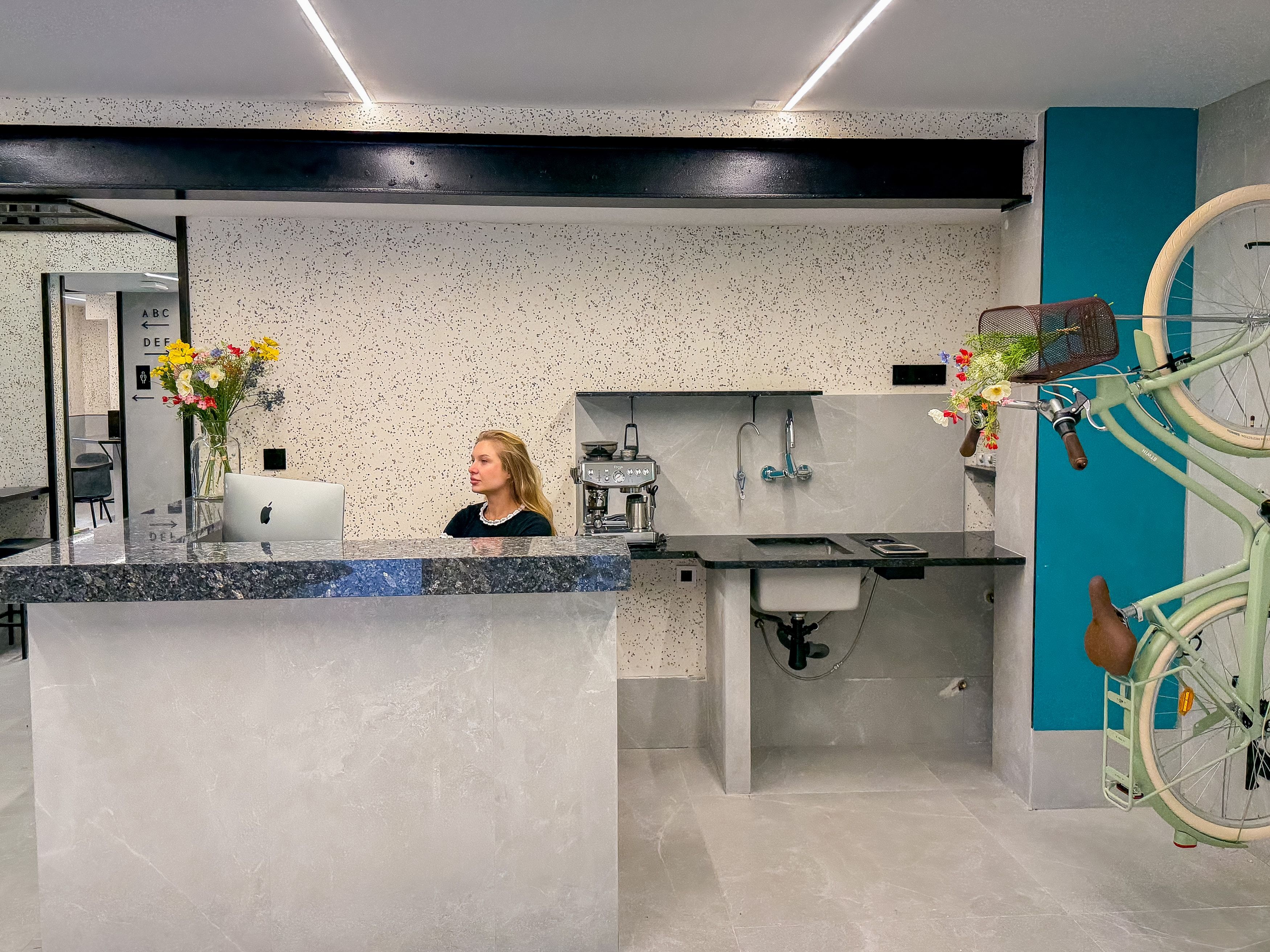 Una zona de recepción moderna con mostrador de mármol, un lavabo y un soporte para bicicletas.