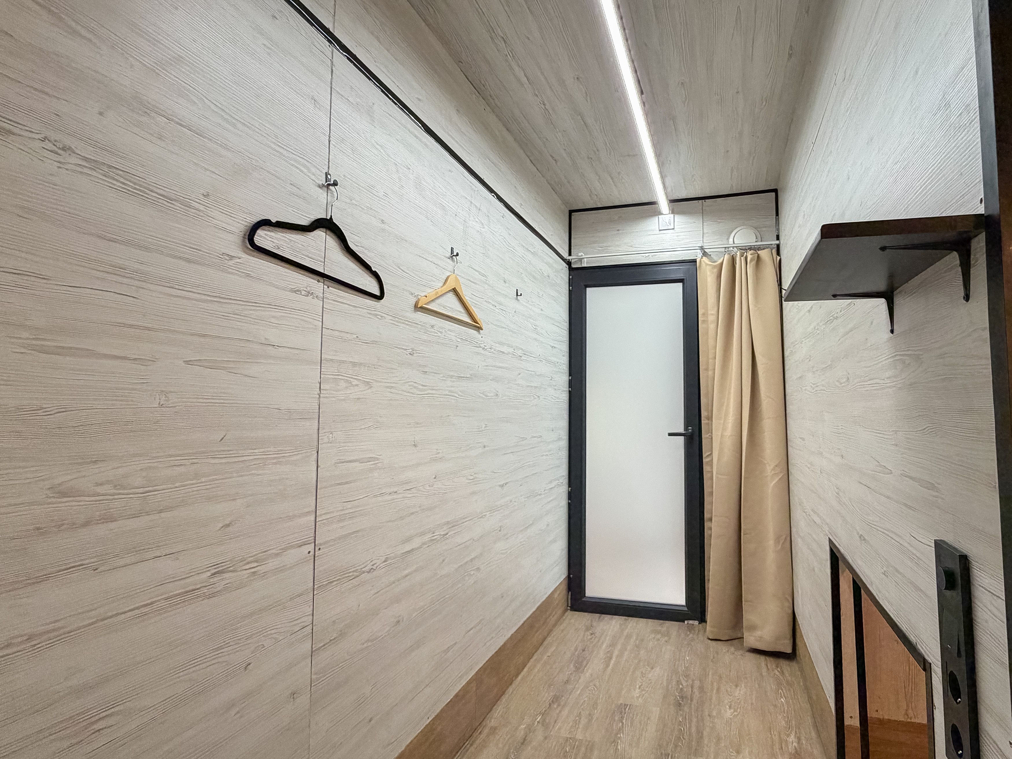 A hallway with wooden walls, a door, and a curtain.