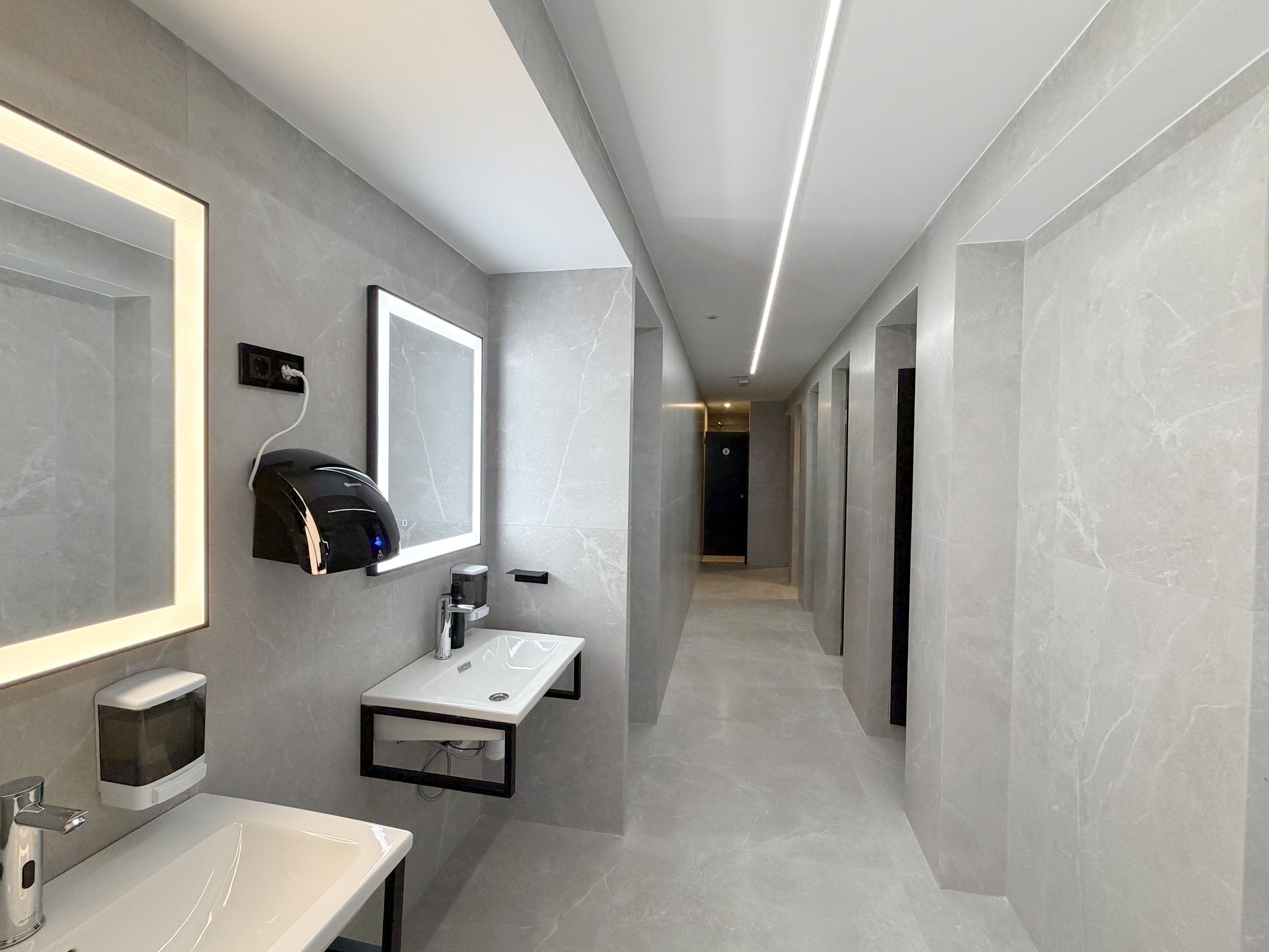 Uma casa de banho moderna com um espelho grande, secador de cabelo, lavatório e um porta-toalhas.