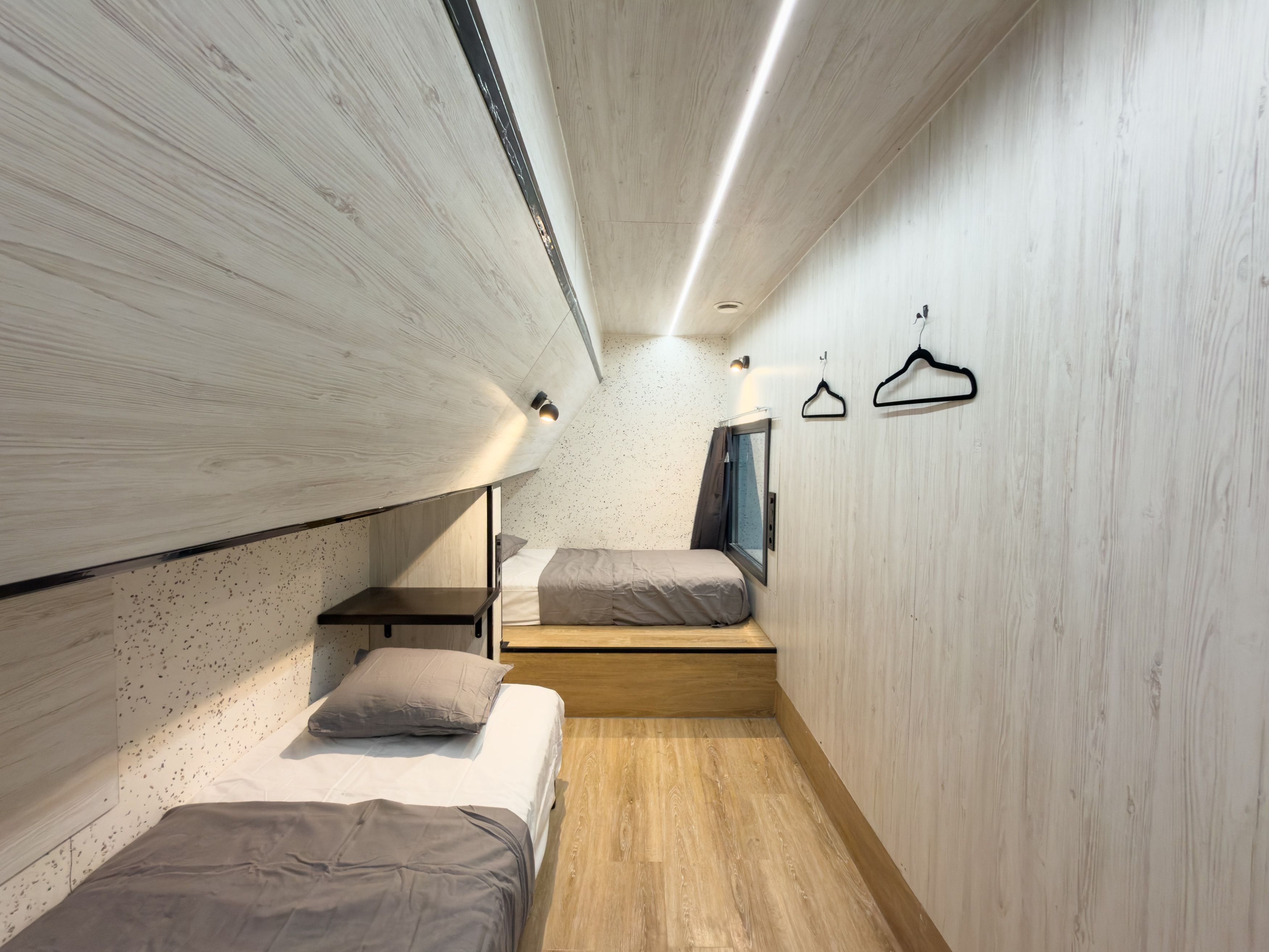 Une chambre à coucher de taille réduite, équipée d’un lit superposé, d’un petit bureau et d’un luminaire suspendu.