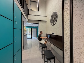 A modern interior with teal lockers, a bar area, and a seating bench.