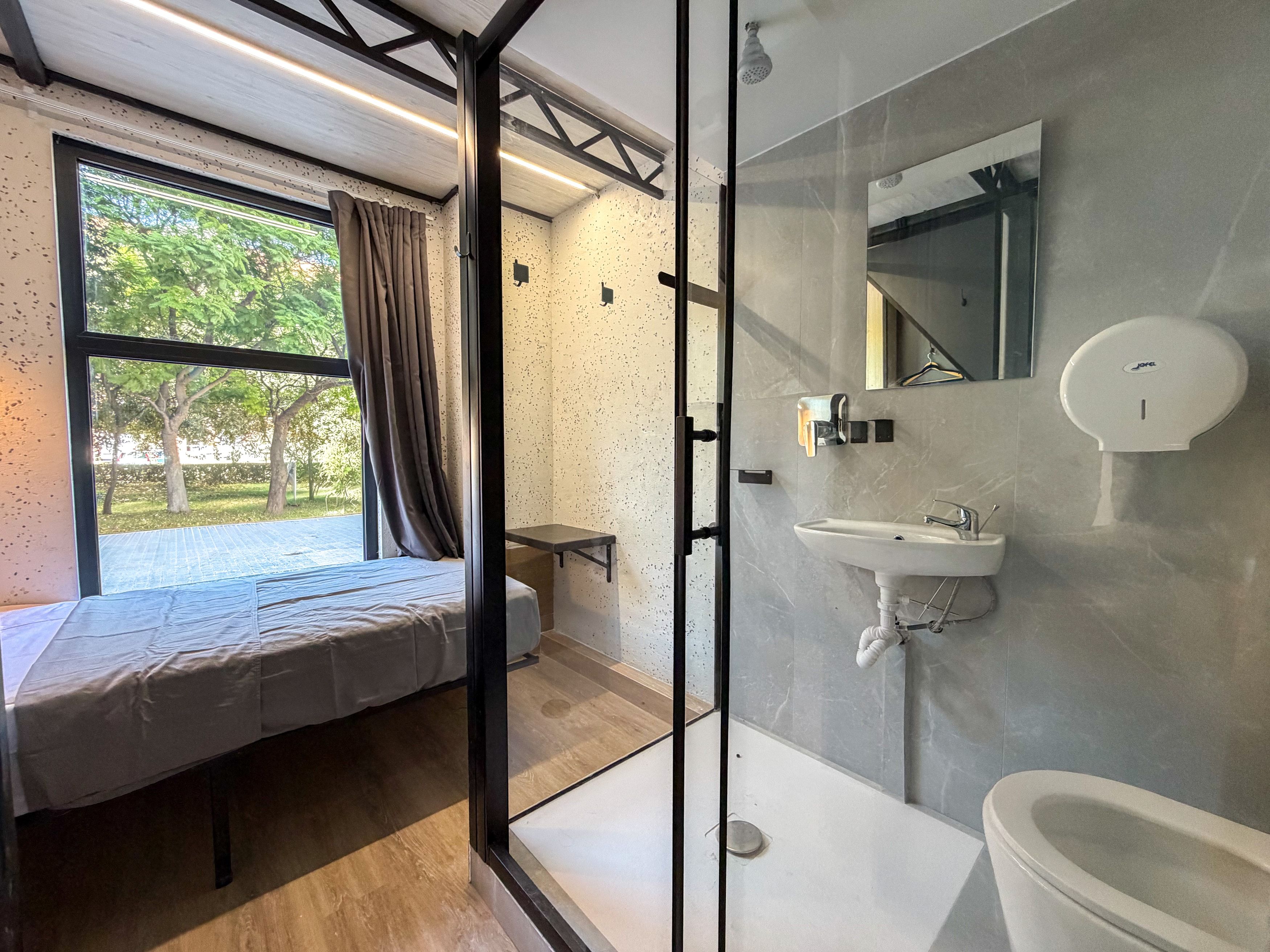 Un baño moderno con mampara de vidrio, lavamanos, espejo e inodoro.