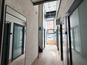 A corridor with glass doors, numbered signs, and a view of the street outside.