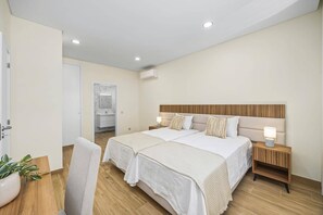 A hotel room with a double bed, bedside tables with lamps, a wooden headboard, and a bathroom visible through an open door. - Villa Casa do Pomar by Villa Plus (Olhos de Água)