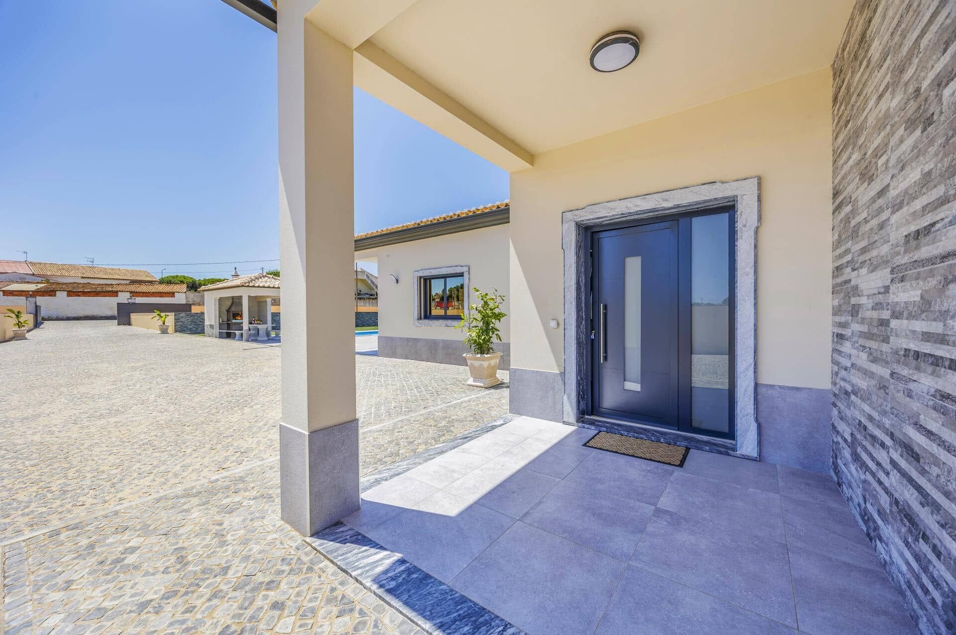 A covered outdoor area with a stone floor, a door, and a potted plant.