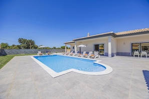 A swimming pool with lounge chairs and a patio area. - Villa Casa do Pomar by Villa Plus (Olhos de Água)