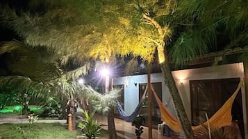 A nighttime outdoor area with a hammock, a small building, and a pathway.
