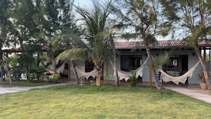 A house with a tiled roof, a hammock, and a well-maintained lawn.
