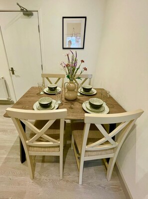 A dining table with four chairs, a vase with flowers, and a framed picture on the wall. - Ridgeways Premium House (Bristol City)
