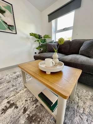 A modern living room with a grey sofa, a coffee table with a tray, a potted plant, and a framed picture on the wall. - Ridgeways Premium House (Bristol City)